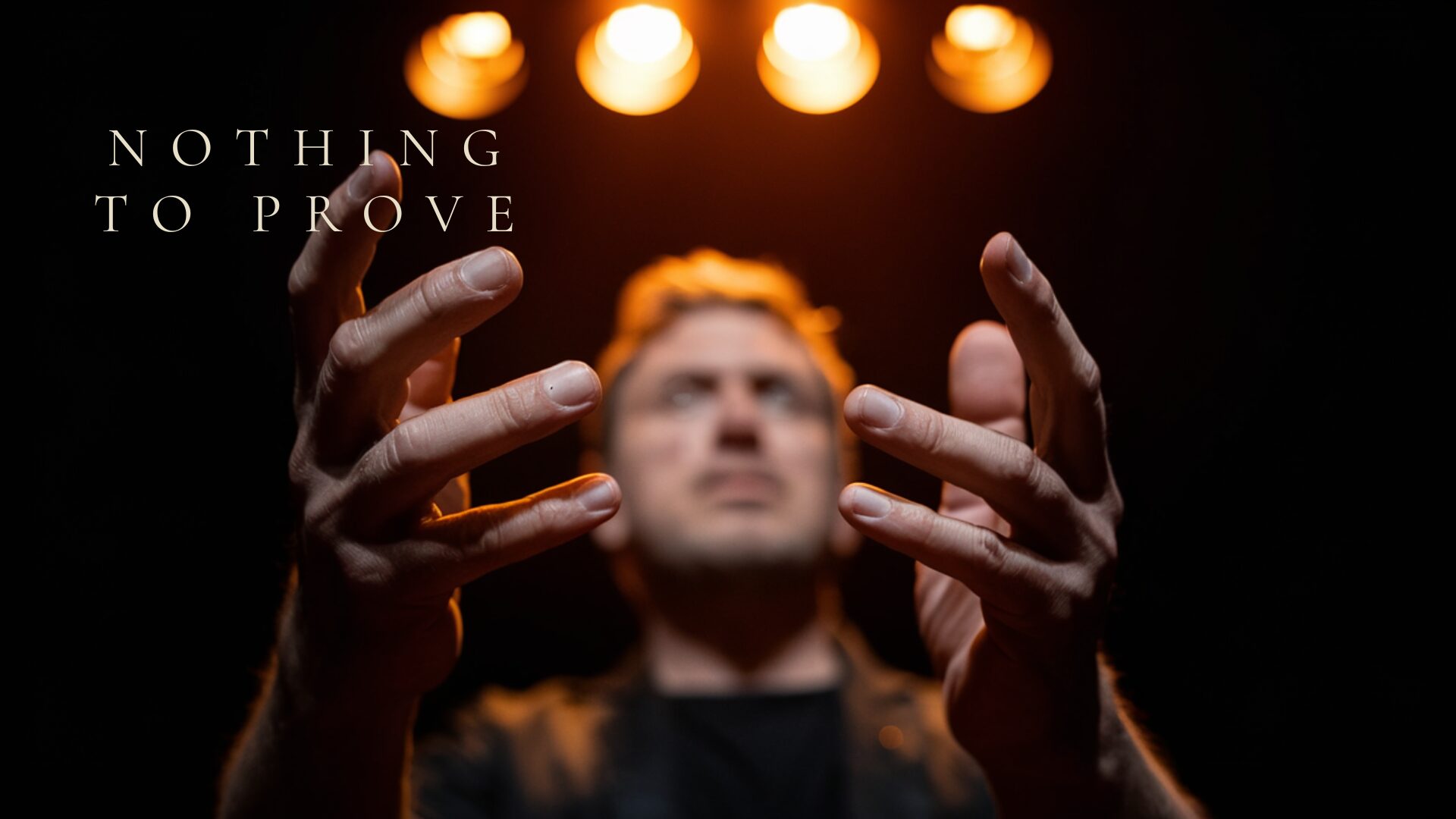 A performer on stage, hands raised in dramatic gesture — Nothing to Prove, a theatrical chamber work by Stephen P. Brown